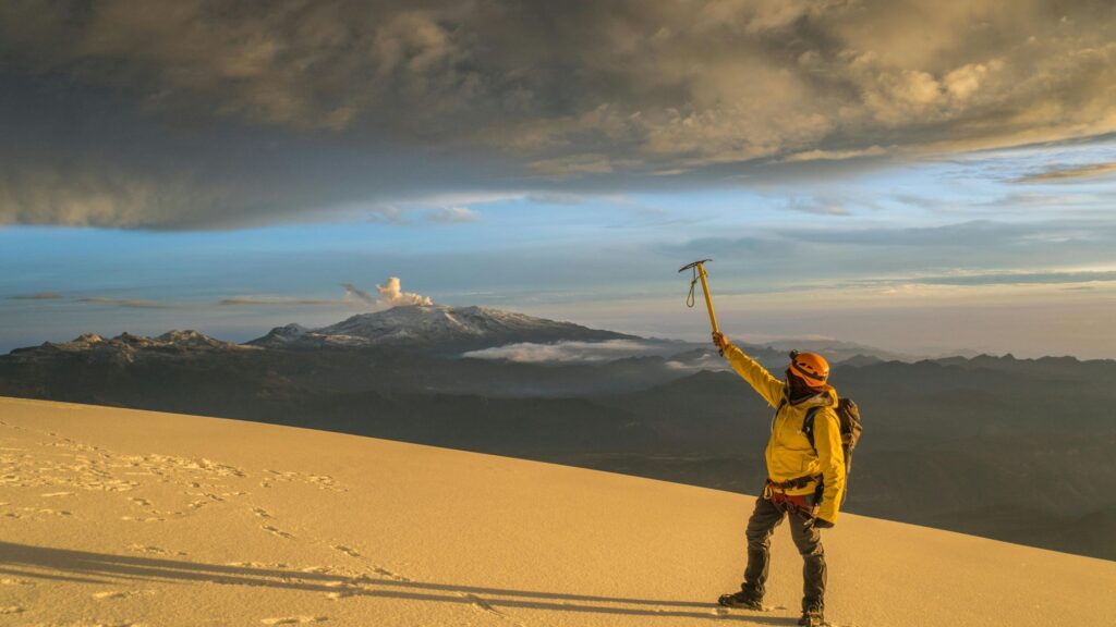 Solo climber standing on Cotopaxi glacier, gazing out over snow-covered peaks and vast Andean landscapes