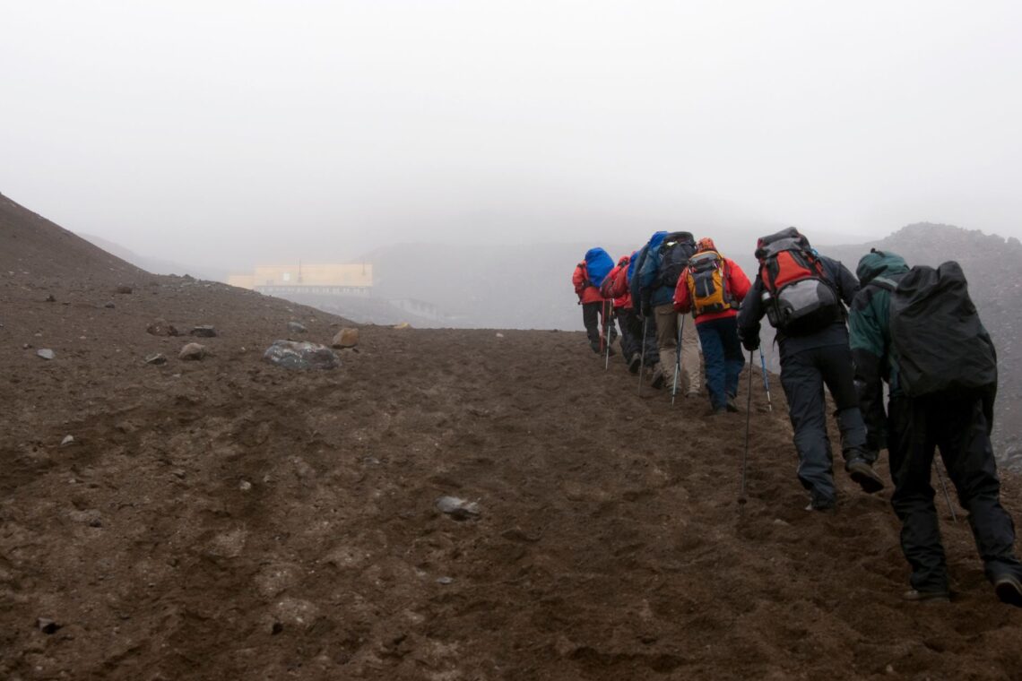 Group of hikers standing near the refuge hut on Cotopaxi Volcano, surrounded by mist and volcanic terrain