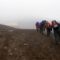 Group of hikers standing near the refuge hut on Cotopaxi Volcano, surrounded by mist and volcanic terrain