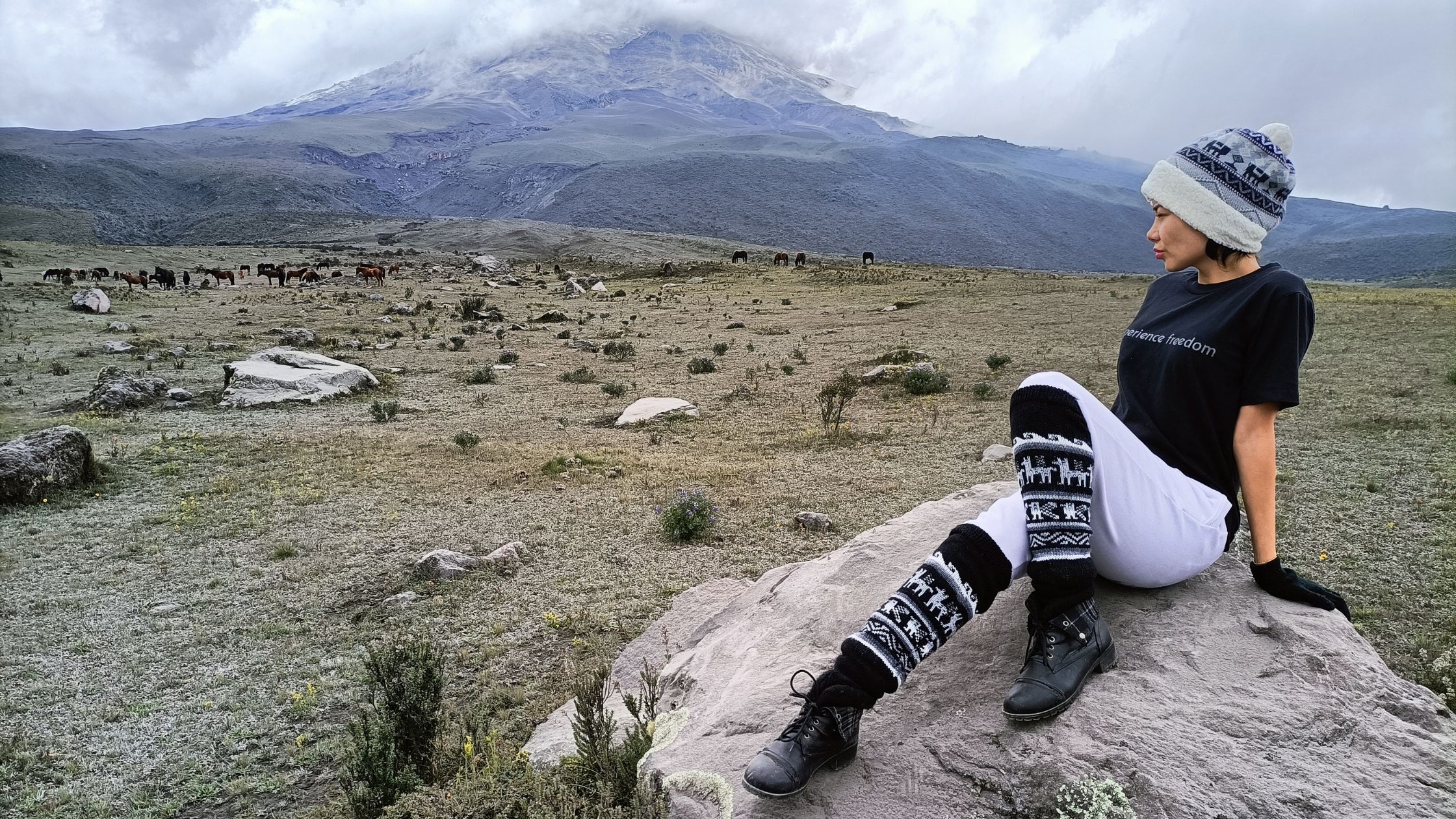 Traveler posing with a Barefoot Expeditions T-shirt in front of Cotopaxi Volcano, embodying the spirit of adventure and freedom