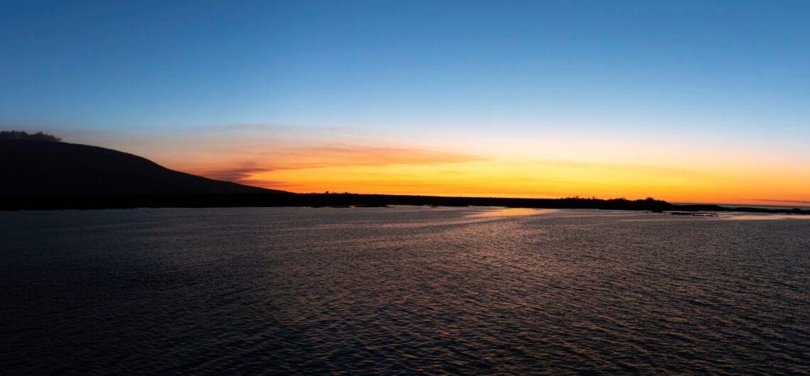 Golden sunset over Fernandina Island, the youngest and most volcanically active island in the Galápagos. Lava flows meet the Pacific Ocean, creating a dramatic landscape untouched by human presence — a sanctuary for marine iguanas, flightless cormorants, and Galápagos hawks.