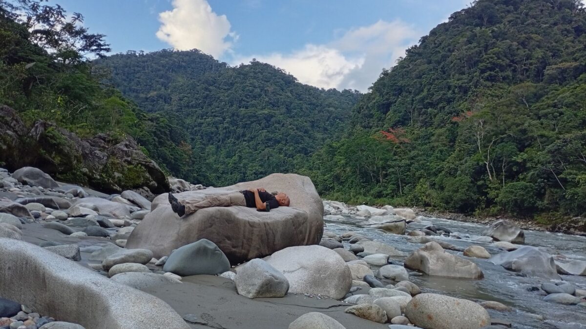 Travelers resting beside a river in the Ecuadorian Amazon during a wellness retreat