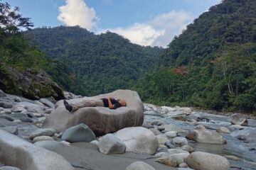 Travelers resting beside a river in the Ecuadorian Amazon during a wellness retreat