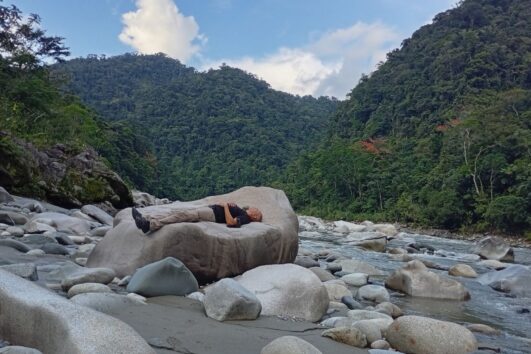 Travelers resting beside a river in the Ecuadorian Amazon during a wellness retreat